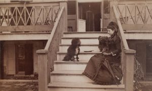 Photo of woman seated on steps with two dogs