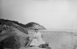 Photo of a woman seated at the beach with a dog