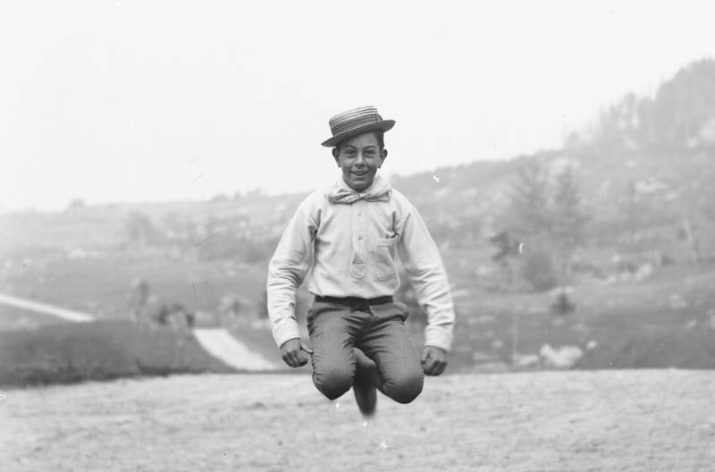 Black and white photograph of a boy jumping.