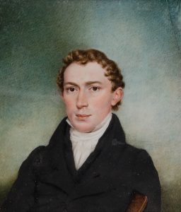 Color photograph of a watercolor painting of a young white man with slightly curly brown hair and brown eyes. He wears a white cravat and high collar with black vest and jacket. He carries a book under his left arm. He sits in slight three-quarter profile towards the left while looking at the viewer. The background is plain blues, creams and greens suggesting an outdoor or atmospheric background without details.