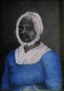 Color photograph of a watercolor painting of an older Black woman wearing a white cap that ties under her chin, white kerchief tucked into a blue dress, and a gold bead necklace around her neck. She looks at the viewer from a three-quarter profile facing left. The background is gray, lighter on the right fading to black on the left.