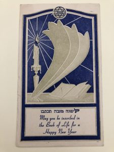 Image of a New Year's card. The card depicts a burning candle on the left, an open book on the right, and text at the bottom.