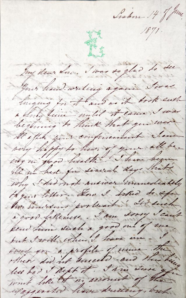 Color photograph of a black ink handwritten letter with a green "E" monogram at the top of the page. The E is made of filigree vines and has a crown over the center line. 