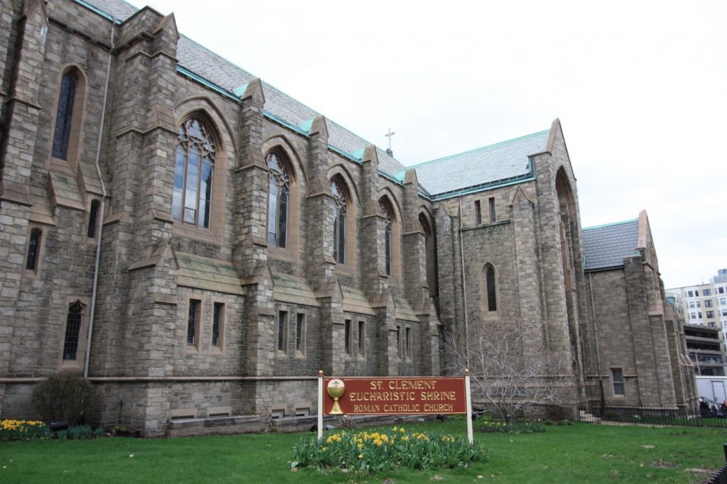 The large gray stone exterior of St. Clement Eucharistic Shrine, with pointed arches throughout.