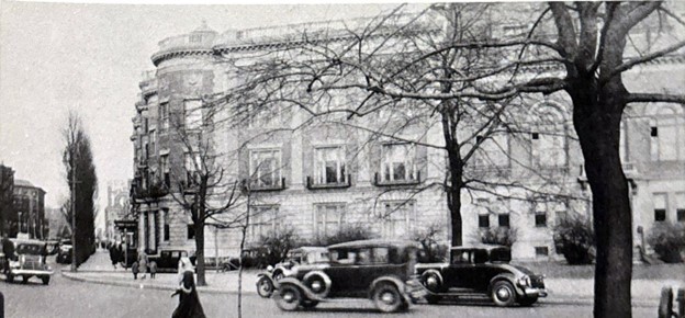 A black and white photo of the Massachusetts Historical Society building in 1932. Pedestrians and old cars pass by in the foreground.