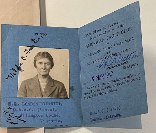 Color photograph of the inside of the Worker's Pass from the previous image with a black and white photograph on the left hand side of an older white woman with dark hair pulled back, she wears a dark jacket and a light shirt or dress. On the right it reads "American Eagle Club" and in a blue stamp, "9 MAR 1942."