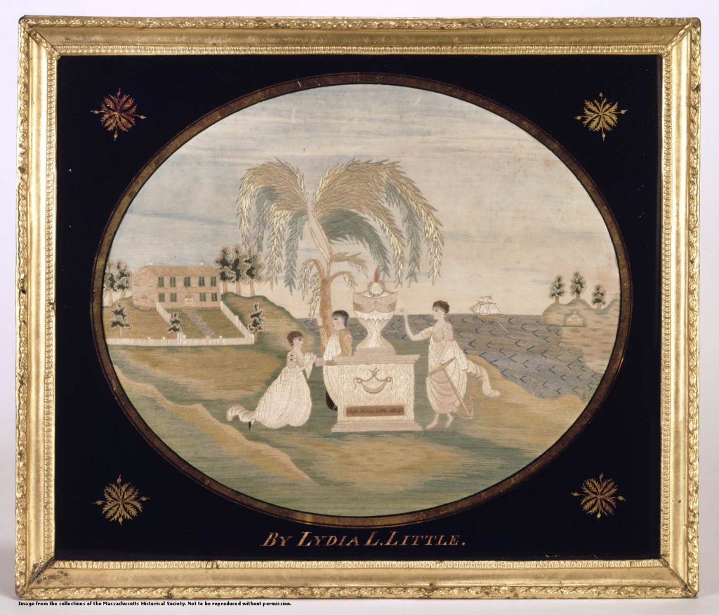 A color photograph of a framed embroidered cloth in an oval shape with black filling in from the oval to the frame. The image is of three children surrounding an urn on a gravestone with a weeping willow behind them, a house in the background and a ship in a harbor on the other side. 