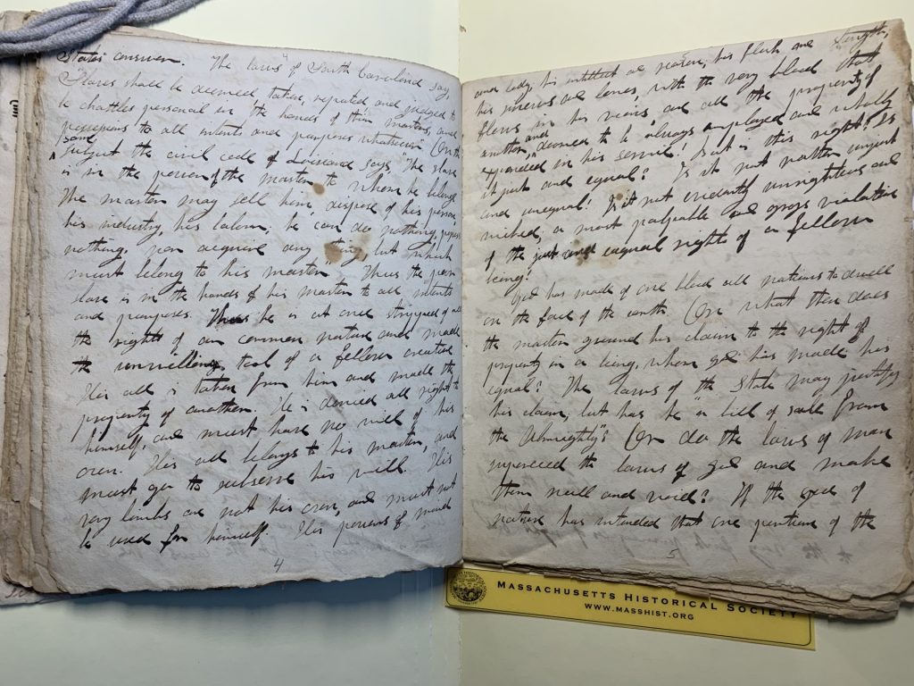 Color photograph of an open book with black ink handwriting on both sides. The text is not very legible. 