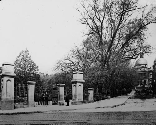 View of gates at entrance to Boston Common, corner of Park and Tremont Streets, with view also of Park Street and the State House, Boston Lantern slide