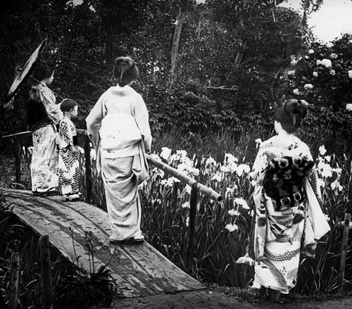 Three women and a child standing on or near a wooden footbridge, Japan(?) Lantern slide