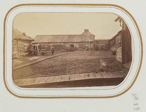 View of buildings surrounding a dirt yard with several unidentified people Carte de visite