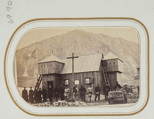 View of a group of unidentified men in front of wooden structure, mountains in background Carte de visite