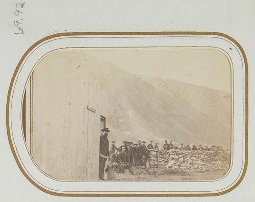 Group of unidentified men posed near stone fence, mountains in background Carte de visite