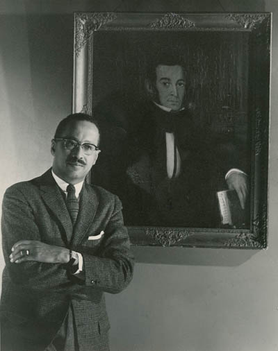 Howard DeGrasse Asbury standing next to a portrait of Isaiah George DeGrasse Photograph