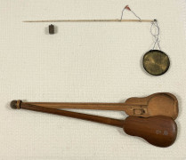 Slim ivory stick with pointed ends two suspension threads with red silk tassels attached near one end, through which black silk cords attach the turned-brass weighing pan. A two-piece bamboo case in the shape of a guitar with a long arm and two Chinese characters inlaid in silver points on the lid lies partially open revealing a s a hand-carved cavity to fit the scale.